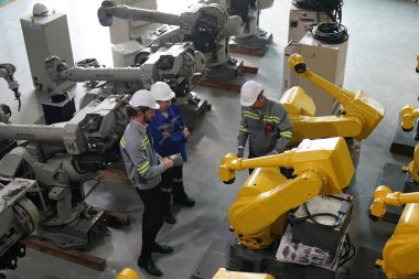 Robot mühendisleri fabrika deposunda robotik kolun bakımı üzerinde çalışıyorlar. İş teknolojisi.