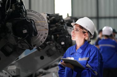Robot mühendisi fabrika deposunda robotik kolun bakımı üzerinde çalışıyor. İş teknolojisi.