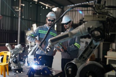 Robot mühendisleri fabrika deposunda robotik kolun bakımı üzerinde çalışıyorlar. İş teknolojisi.