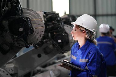 Robot mühendisi fabrika deposunda robotik kolun bakımı üzerinde çalışıyor. İş teknolojisi.