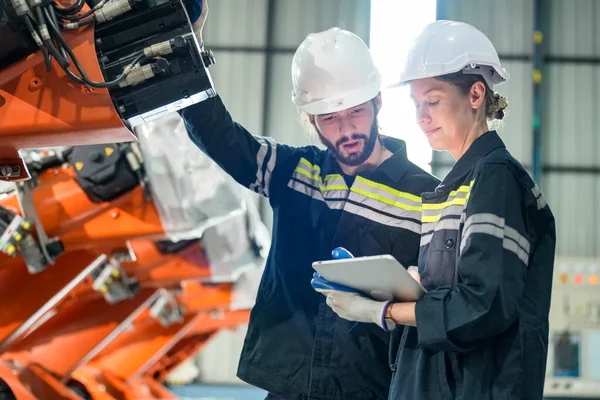 stock image technicians programming  a robot arm in a factory. Apprentice engineers programming robot in factory.