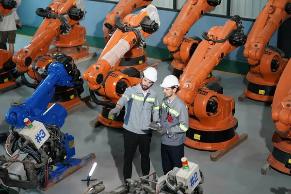Robot mühendisleri fabrika deposunda robotik kolun bakımı üzerinde çalışıyorlar. İş teknolojisi.