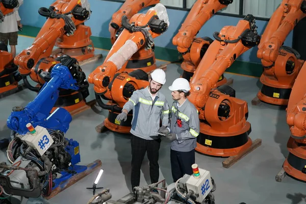 Robot mühendisleri fabrika deposunda robotik kolun bakımı üzerinde çalışıyorlar. İş teknolojisi.