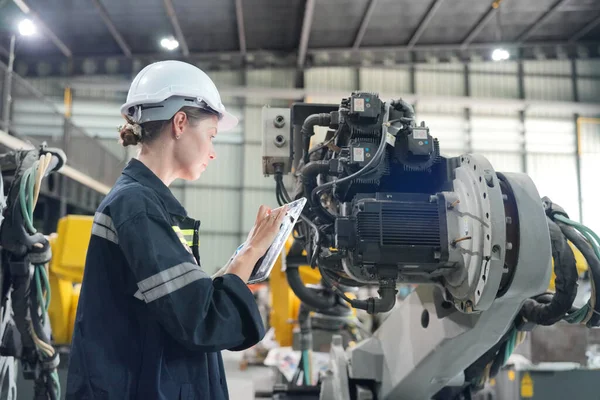 Teknisyen bir robot kolu dijital tabletle programlar ve bir fabrikada robot montajı yapar. Çırak mühendisleri fabrikada robot programlıyorlar..