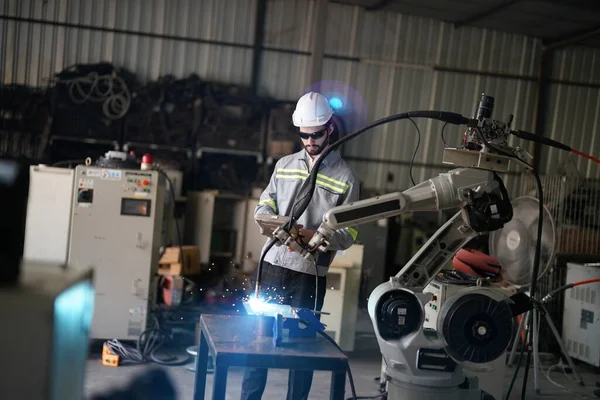 Robot mühendisi fabrika deposunda robotik kolun bakımı üzerinde çalışıyor. İş teknolojisi.