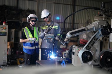 Robot mühendisleri fabrika deposunda robotik kolun bakımı üzerinde çalışıyorlar. İş teknolojisi.