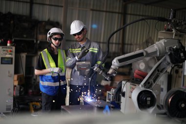 Robot mühendisleri fabrika deposunda robotik kolun bakımı üzerinde çalışıyorlar. İş teknolojisi.