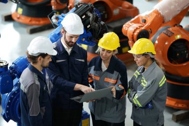 Robot mühendisleri fabrika deposunda robotik kolun bakımı üzerinde çalışıyorlar. İş teknolojisi.