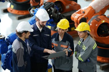 Robot mühendisleri fabrika deposunda robotik kolun bakımı üzerinde çalışıyorlar. İş teknolojisi.