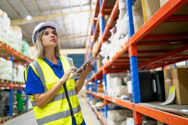 Depo çalışanı envanteri kontrol ediyor. Envanter raflarındaki ürünler. Depoda envanter yapan bir işçi. Üniformalı bir görevli depoda envanter çıkarıyor. arz zinciri kavramı