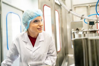 Elektrik santrali için ters osmoz sisteminde çalışan bir kadın. Endüstri için RO sistemi, endüstriyel kimyasallar, enerji santrali, petrol ve gaz gibi borularla kurulması popüler ekipmanlar. Şişeleme fabrikasında genç bayan işçi su şişelerini kontrol ediyor. 