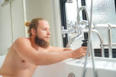 Modern banyo lüks içinde banyo yapan rahat genç adam. Spa, sağlık, vücut bakımı konsepti