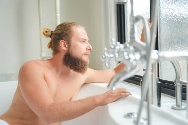Modern banyo lüks içinde banyo yapan rahat genç adam. Spa, sağlık, vücut bakımı konsepti