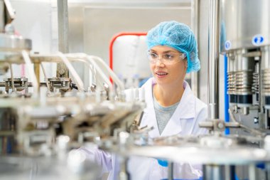 Elektrik santrali için ters osmoz sisteminde çalışan bir kadın. Endüstri için RO sistemi, endüstriyel kimyasallar, enerji santrali, petrol ve gaz gibi borularla kurulması popüler ekipmanlar. Şişeleme fabrikasında su şişelerini kontrol eden genç ve mutlu bir kadın işçi. 