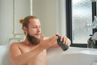 Modern banyo lüks içinde banyo yapan rahat genç adam. Spa, sağlık, vücut bakımı konsepti