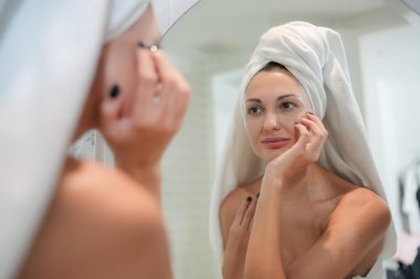 Cilt bakım konsepti. Aynaya bakan, dokunan bir kadın ve tuvalette mükemmel bir ten. Seçici Odaklanma