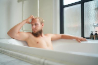 Modern banyo lüks içinde banyo yapan rahat genç adam. Spa, sağlık, vücut bakımı konsepti