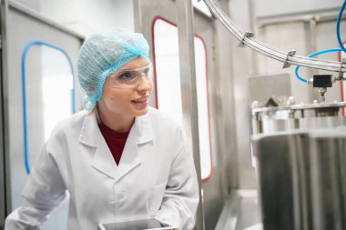 Elektrik santrali için ters osmoz sisteminde çalışan bir kadın. Endüstri için RO sistemi, endüstriyel kimyasallar, enerji santrali, petrol ve gaz gibi borularla kurulması popüler ekipmanlar. Şişeleme fabrikasında genç bayan işçi su şişelerini kontrol ediyor.