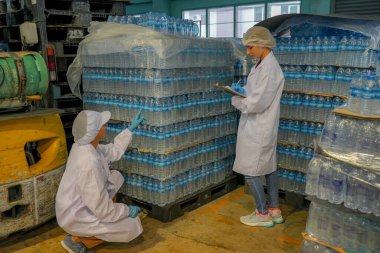 Elektrik santrali için ters osmoz sisteminde çalışan bir kadın. Endüstriyel endüstri için RO sistemi, endüstriyel kimyasallar, elektrik santrali gibi borularla kurulması popüler ekipmanlar. Şişeleme fabrikasında su şişelerini kontrol eden genç ve mutlu bir kadın işçi.  