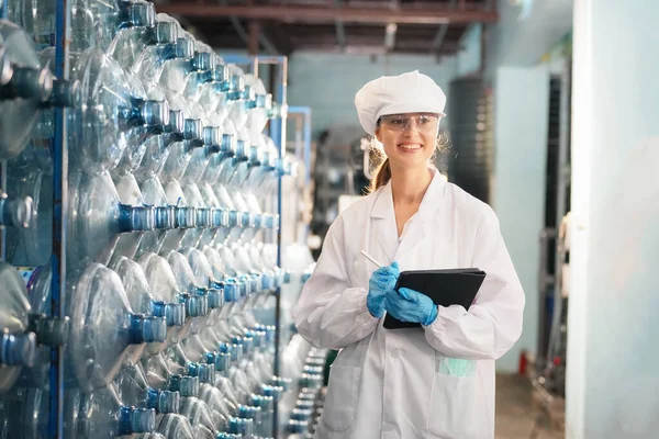 Woman working at Reverse osmosis system for power plant. RO system for industry, equipment which popular to install with pipe at industrial such chemical, power plant, oil and gas. Young happy female worker in bottling factory checking water bottles