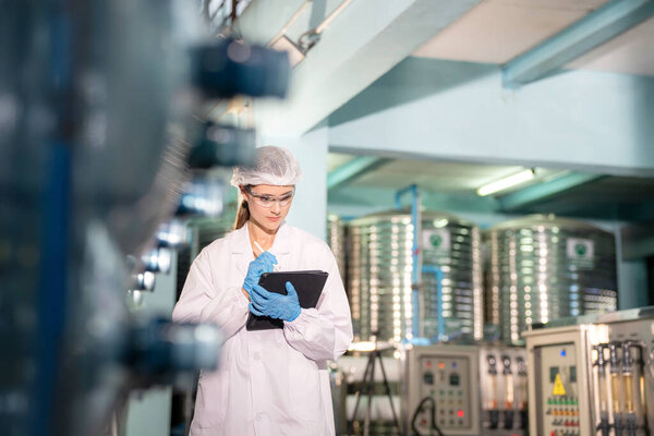 Женщина, работающая в системе обратного осмоса для электростанции. RO система для промышленности, оборудование, которое популярно для установки с трубами на промышленных таких химических, электростанций. Молодая счастливая работница на заводе по розливу воды проверяет бутылки  