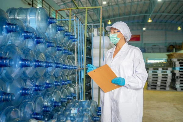Woman working at Reverse osmosis system for power plant. RO system for industry, equipment which popular to install with pipe at industrial such chemical, power plant. Young happy female worker in bottling factory checking water bottles