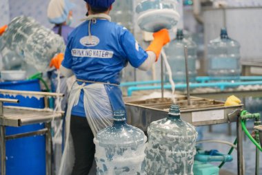 Elektrik santrali için ters osmoz sisteminde çalışan bir kadın. Endüstriyel endüstri için RO sistemi, endüstriyel kimyasallar, elektrik santrali gibi borularla kurulması popüler ekipmanlar. Şişeleme fabrikasında su şişelerini kontrol eden genç ve mutlu bir kadın işçi.  