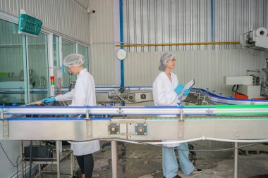 Elektrik santrali için ters osmoz sisteminde çalışan bir kadın. Endüstriyel endüstri için RO sistemi, endüstriyel kimyasallar, elektrik santrali gibi borularla kurulması popüler ekipmanlar. Şişeleme fabrikasında su şişelerini kontrol eden genç ve mutlu bir kadın işçi.  