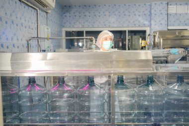 Elektrik santrali için ters osmoz sisteminde çalışan bir kadın. Endüstri için RO sistemi, endüstriyel kimyasallar, enerji santrali, petrol ve gaz gibi borularla kurulması popüler ekipmanlar. Şişeleme fabrikasında su şişelerini kontrol eden genç ve mutlu bir kadın işçi.