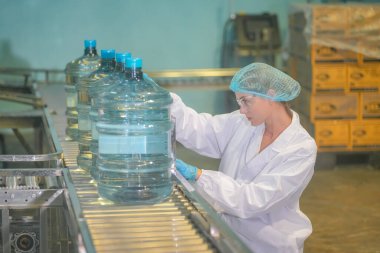 Elektrik santrali için ters osmoz sisteminde çalışan bir kadın. Endüstriyel endüstri için RO sistemi, endüstriyel kimyasallar, elektrik santrali gibi borularla kurulması popüler ekipmanlar. Şişeleme fabrikasında su şişelerini kontrol eden genç ve mutlu bir kadın işçi.  