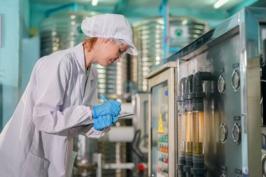 Elektrik santrali için ters osmoz sisteminde çalışan bir kadın. Endüstri için RO sistemi, endüstriyel kimyasallar, enerji santrali, petrol ve gaz gibi borularla kurulması popüler ekipmanlar. Şişeleme fabrikasında su şişelerini kontrol eden genç ve mutlu bir kadın işçi. 