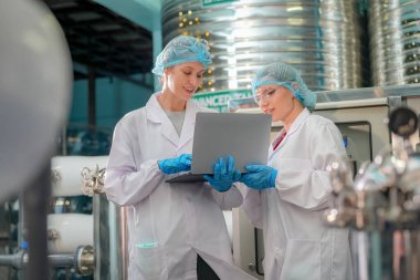 Elektrik santrali için ters osmoz sisteminde çalışan kadınlar. Endüstri için RO sistemi, endüstriyel kimyasallar, enerji santrali, petrol ve gaz gibi borularla kurulması popüler ekipmanlar. Şişeleme fabrikasında genç bayan işçiler su şişelerini kontrol ediyor. 