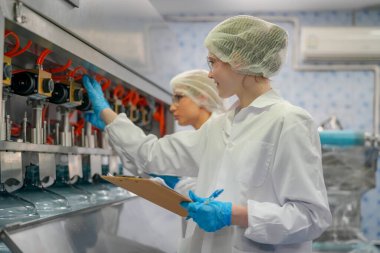 Elektrik santrali için ters osmoz sisteminde çalışan kadınlar. Endüstri için RO sistemi, endüstriyel kimyasallar, enerji santrali, petrol ve gaz gibi borularla kurulması popüler ekipmanlar. Şişeleme fabrikasında genç bayan işçiler su şişelerini kontrol ediyor. 