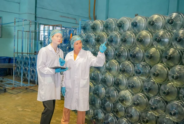 Women working at Reverse osmosis system for power plant. RO system for industry, equipment which popular to install with pipe at industrial such chemical, power plant, oil and gas. Young  female workers in bottling factory checking water bottles