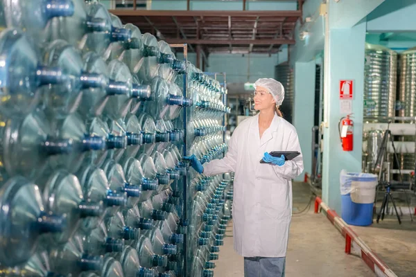 Woman working at Reverse osmosis system for power plant. RO system for industry, equipment which popular to install with pipe at industrial such chemical, power plant, oil and gas. Young female worker in bottling factory checking water bottles