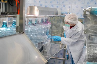 Elektrik santrali için ters osmoz sisteminde çalışan bir kadın. Endüstri için RO sistemi, endüstriyel kimyasallar, enerji santrali, petrol ve gaz gibi borularla kurulması popüler ekipmanlar. Şişeleme fabrikasında su şişelerini kontrol eden genç ve mutlu bir kadın işçi. 