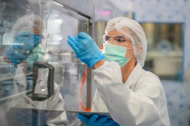 Elektrik santrali için ters osmoz sisteminde çalışan bir kadın. Endüstri için RO sistemi, endüstriyel kimyasallar, enerji santrali, petrol ve gaz gibi borularla kurulması popüler ekipmanlar. Şişeleme fabrikasında genç bayan işçi su şişelerini kontrol ediyor. 