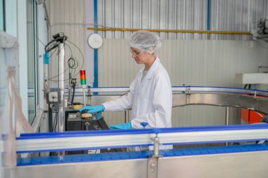 Elektrik santrali için ters osmoz sisteminde çalışan bir kadın. Endüstri için RO sistemi, endüstriyel kimyasallar, enerji santrali, petrol ve gaz gibi borularla kurulması popüler ekipmanlar. Şişeleme fabrikasında genç bayan işçi su şişelerini kontrol ediyor.