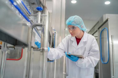 Elektrik santrali için ters osmoz sisteminde çalışan bir kadın. Endüstri için RO sistemi, endüstriyel kimyasallar, enerji santrali, petrol ve gaz gibi borularla kurulması popüler ekipmanlar. Şişeleme fabrikasında genç bayan işçi su şişelerini kontrol ediyor. 
