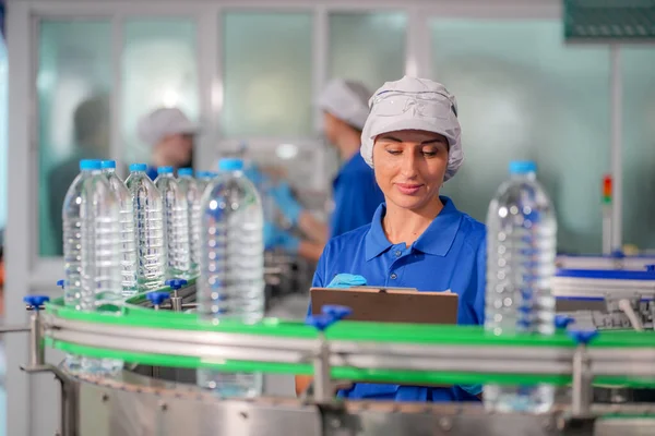 Woman working at Reverse osmosis system for power plant. RO system for industry, equipment which popular to install with pipe at industrial such chemical, power plant, oil and gas. Young happy female worker in bottling factory checking water bottles