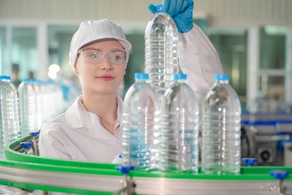 Elektrik santrali için ters osmoz sisteminde çalışan bir kadın. Endüstri için RO sistemi, endüstriyel kimyasallar, enerji santrali, petrol ve gaz gibi borularla kurulması popüler ekipmanlar. Şişeleme fabrikasında su şişelerini kontrol eden genç ve mutlu bir kadın işçi.