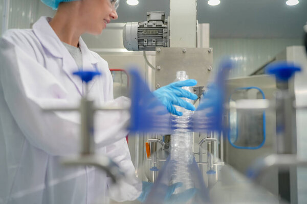 Женщина, работающая в системе обратного осмоса для электростанции. RO система для промышленности, оборудование, которое популярно для установки с трубами на промышленных таких химических, электростанций, нефти и газа. Молодая счастливая работница на заводе по розливу воды проверяет бутылки 