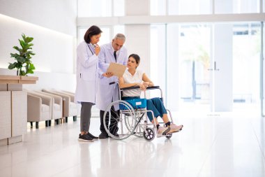 Doktorlar tekerlekli sandalyede oturan kadın hastalarla konuşuyor..
