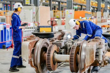 Demiryolu mühendisliği tesisinde lokomotifi inceleyen mühendisler
