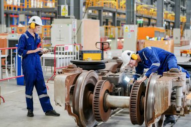Demiryolu mühendisliği tesisinde lokomotifi inceleyen mühendisler