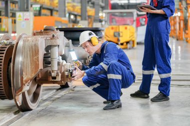 Demiryolu mühendisliği tesisinde lokomotifi inceleyen mühendisler