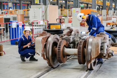 Demiryolu mühendisliği tesisinde lokomotifi inceleyen mühendisler