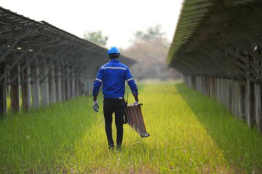 Fotovoltaik çiftlikte çalışan elektrik mühendisi, güneş enerjisi endüstrisindeki aletlerle kontrol ve bakım ekipmanlarını kontrol ediyor..