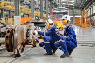 Demiryolu mühendisliği tesisinde lokomotifi inceleyen mühendisler