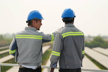 Fotovoltaik bir çiftlikte çalışan elektrik mühendisleri, güneş enerjisi endüstrisindeki aletlerle kontrol ve bakım ekipmanlarını kontrol ediyorlar..